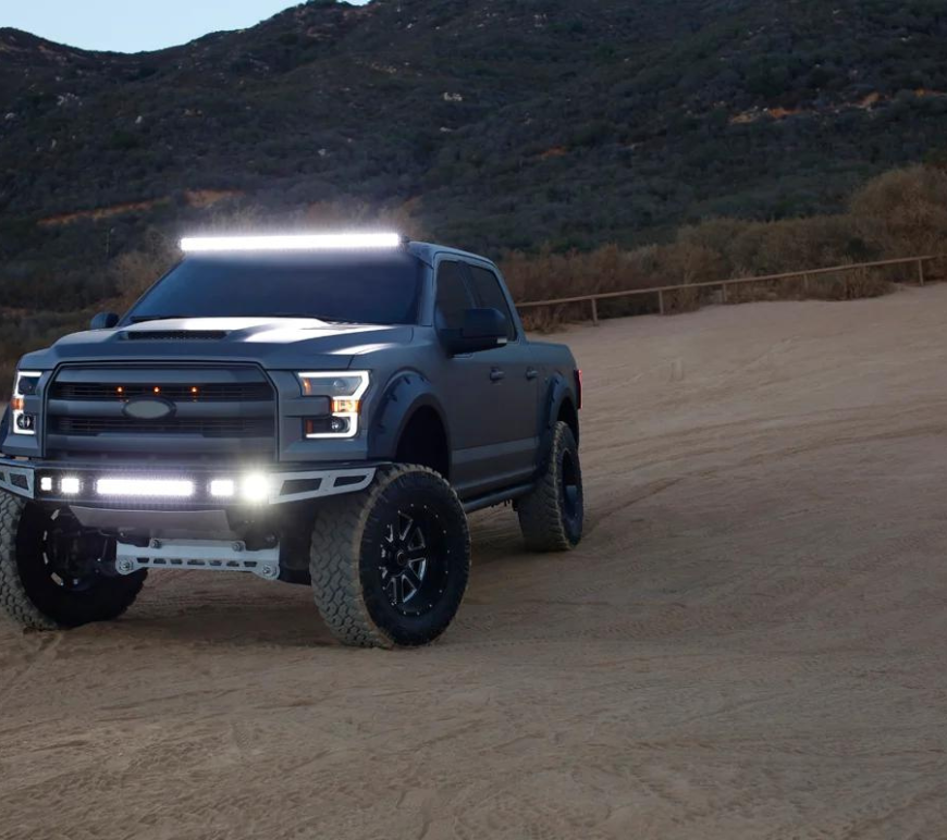 Off-road truck with bright LED light bars in a desert landscape.